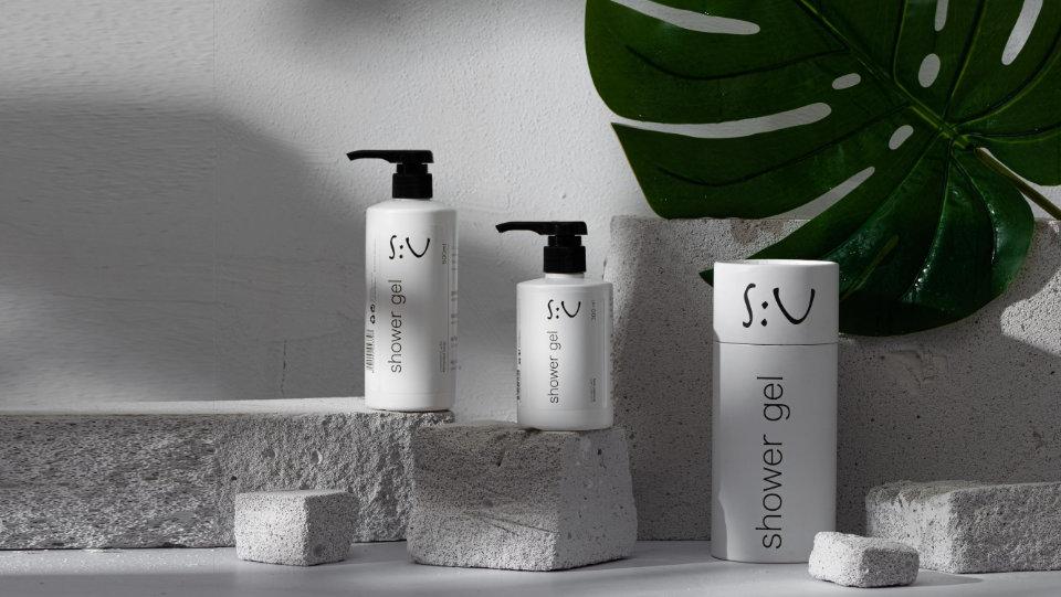 S:U Shower Gel in unterschiedlichen Größen, arrangiert auf Naturstein